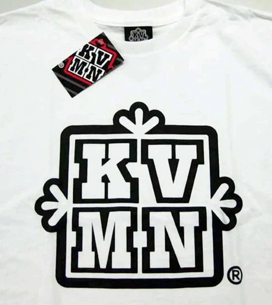 White t-shirt featuring a bold black KV MN logo, with a tag attached showing the brand name and logo design